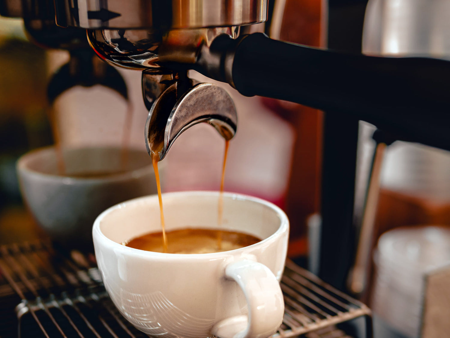 Espresso being poured from a machine into a white cup.